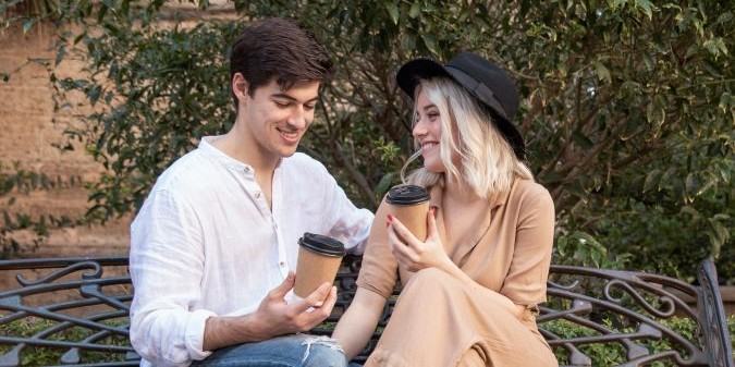 Happy couple enjoying coffee on the bench