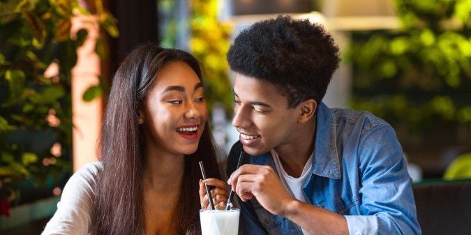 African american guy and girl are seated at a table enjoying milkshakes